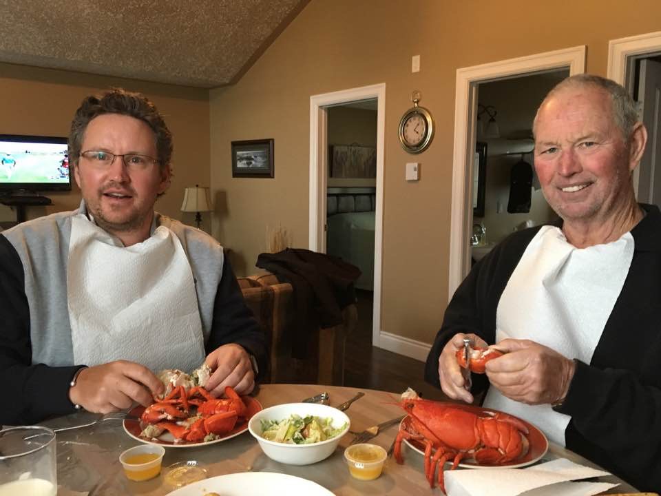 Two people sitting at a table eating lobster.