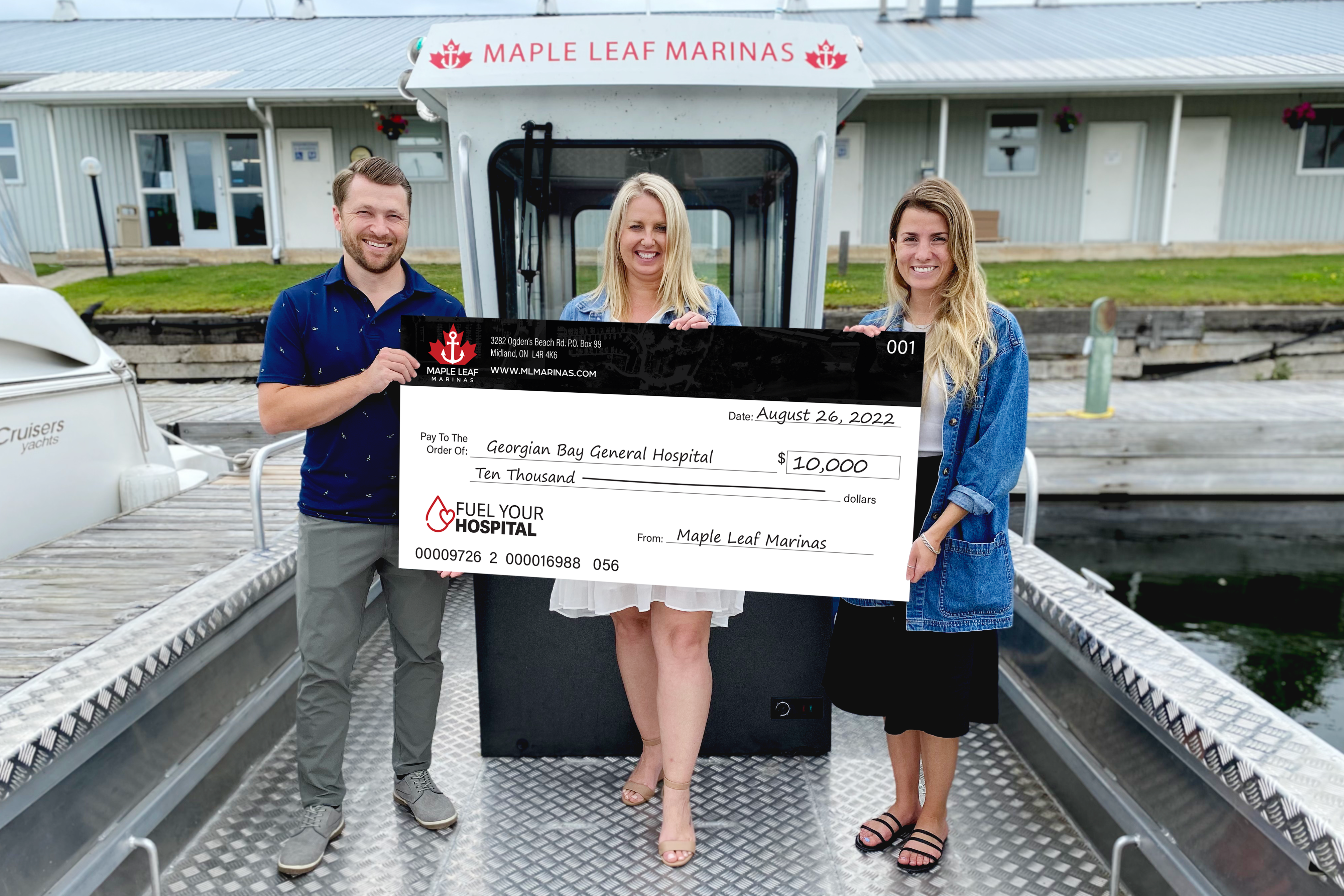 A man and two woman hold a giant cheque for $10,000 for GBGH from Maple Leaf Marinas