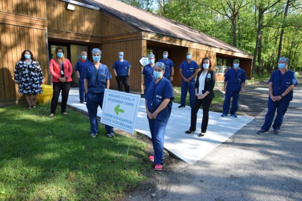 Nurses and staff in masks line both sides of the walkway to the foundation building