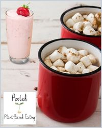 Two red mugs of hot chocolate with marshmallows and a strawberry milkshake