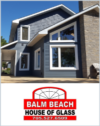 A blue sided house wth white trimmed windows. Below is the Balm Beach House of Glass logo