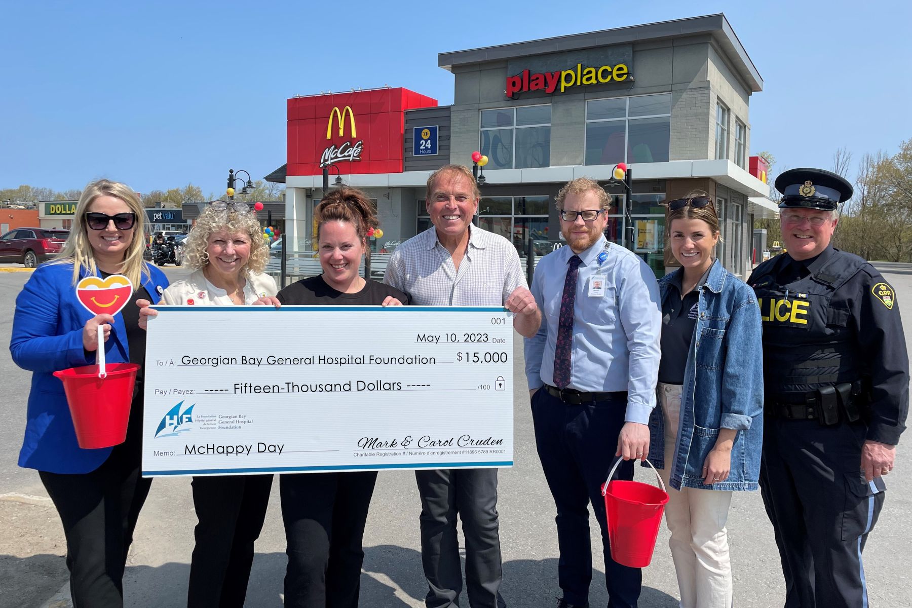 Four woman, two men and a male police officer stand outside the Midland McDonalds restaurant with a cheque for $15,000 from Mark and Carol Cruden - proceeds from McHappy Day.