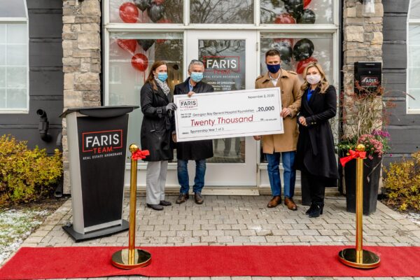 Four people with a big cheque for $20,000 from the Farris Team
