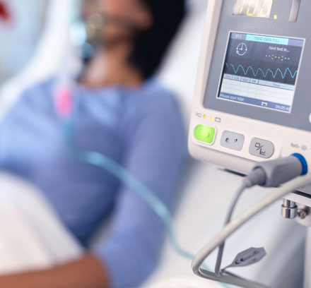 A woman hooked up to an EKG machine while lying in a hospital bed