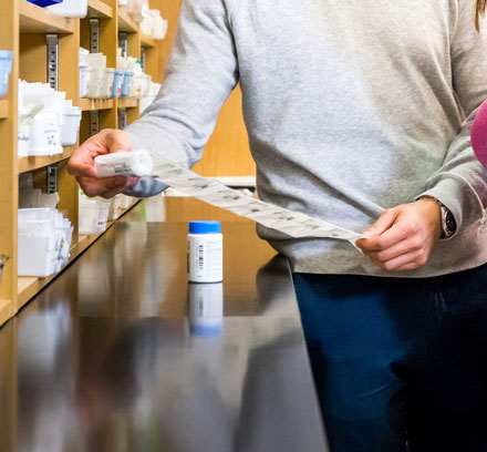 A man looking at a prescription list in a pharmacy