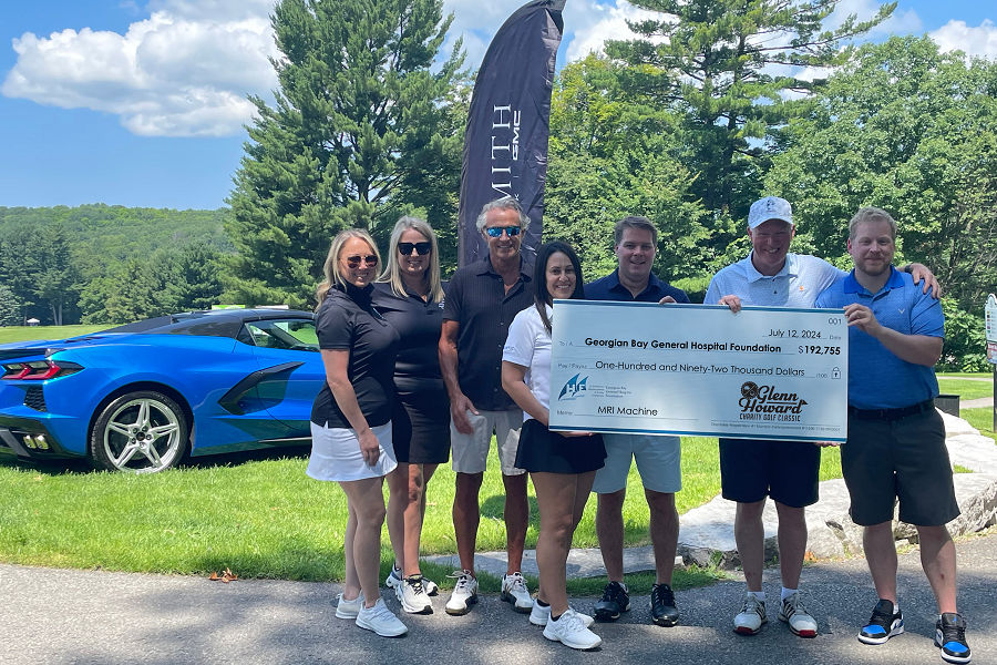 Seven people holding a big cheque on a golf course.