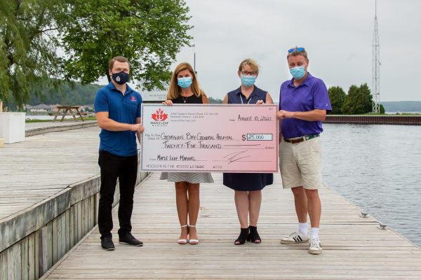 Four people hold up a cheque for $25,000 fr the GBGH from Maple Leaf Marina