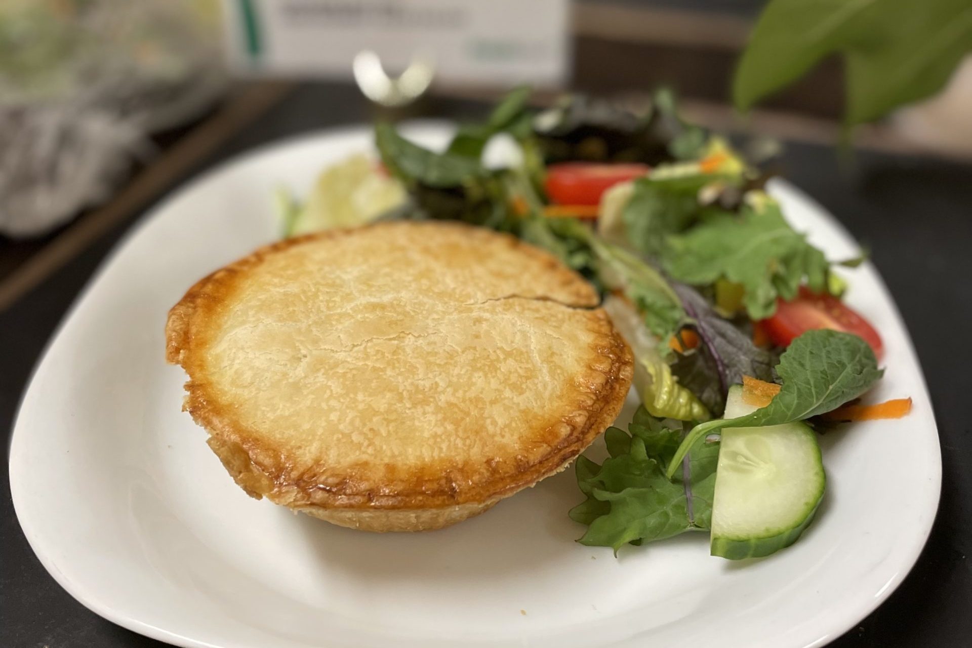 A meat pie and salad on a white plate