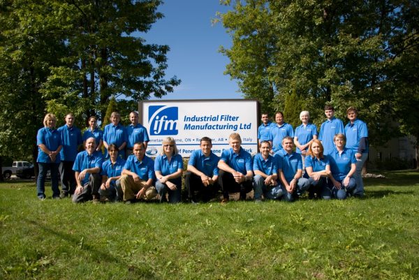 a large group of people in blue shirts posing for a picture outside on a sunny day.