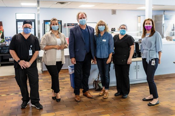 Six people pose wearing masks, some in scrubs and some wearing outdoor clothing