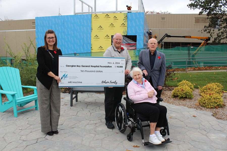 Woman accepts a large cheque from a man and two older adults