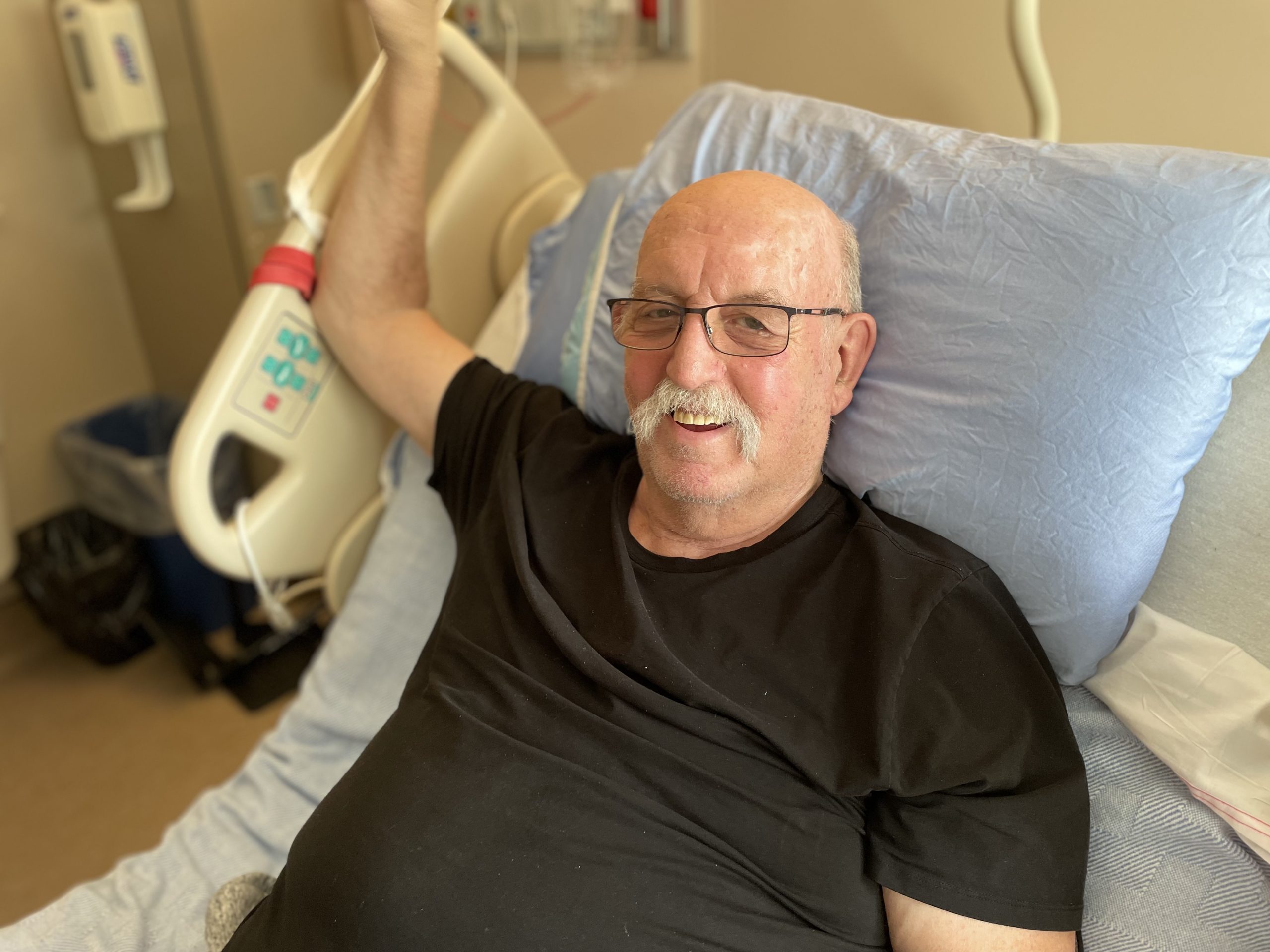 Man smiling in a hospital bed.