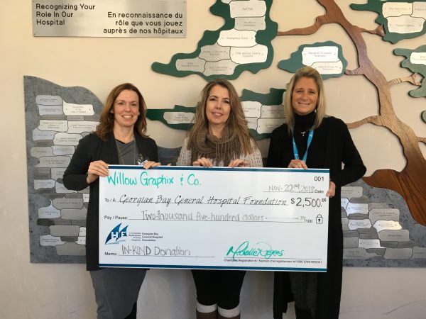 Three women hold a giant cheque for $2,500 from Willow Graphix