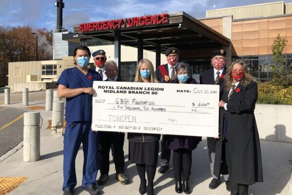 Eight people including Legion members wearing poppies hold a giant cheque for the GBGH foundation to buy Tonpens