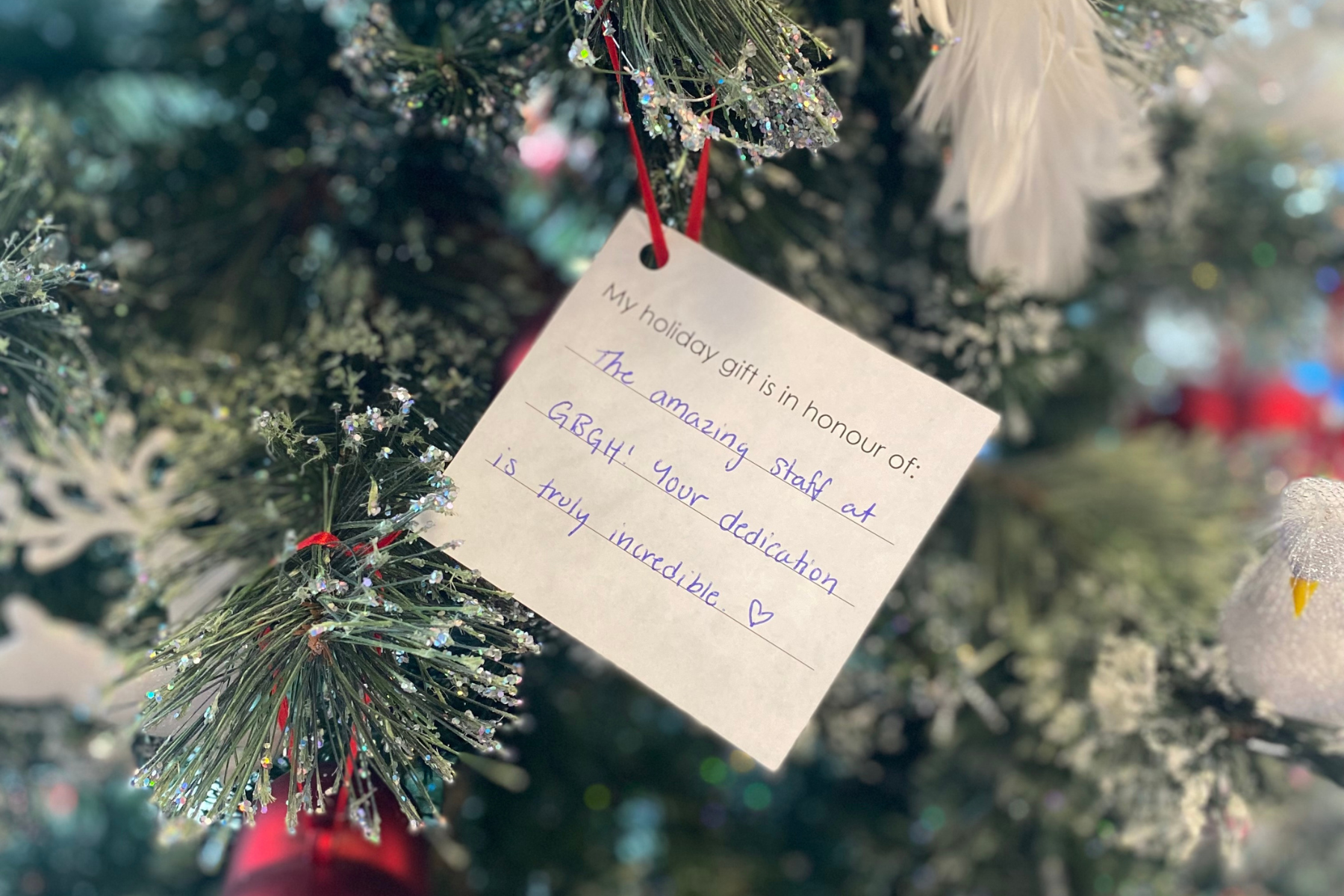 small card with a note thanking amazing staff of the hospital, displayed on a festive spruce tree.