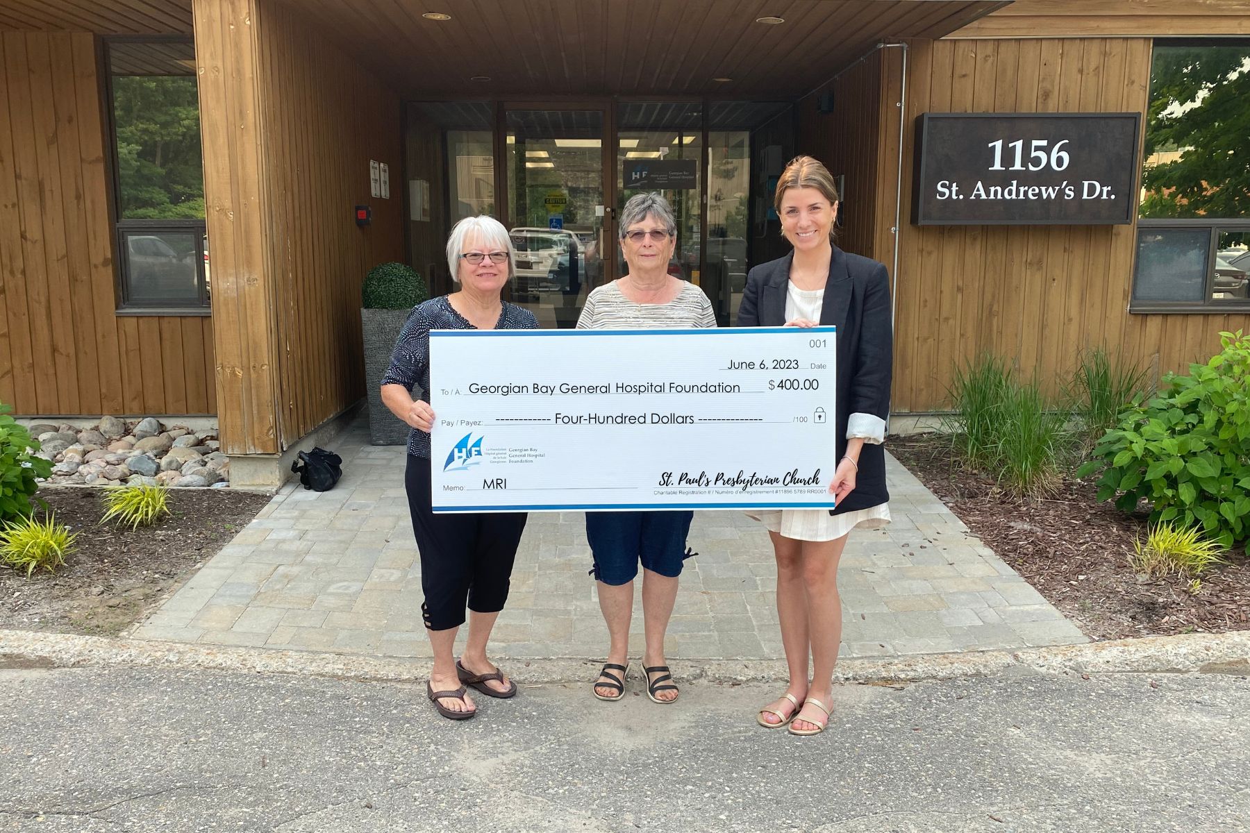 Three women hold a giant cheque for $400 towards the MRI fund from St Paul's Presbyterian Church