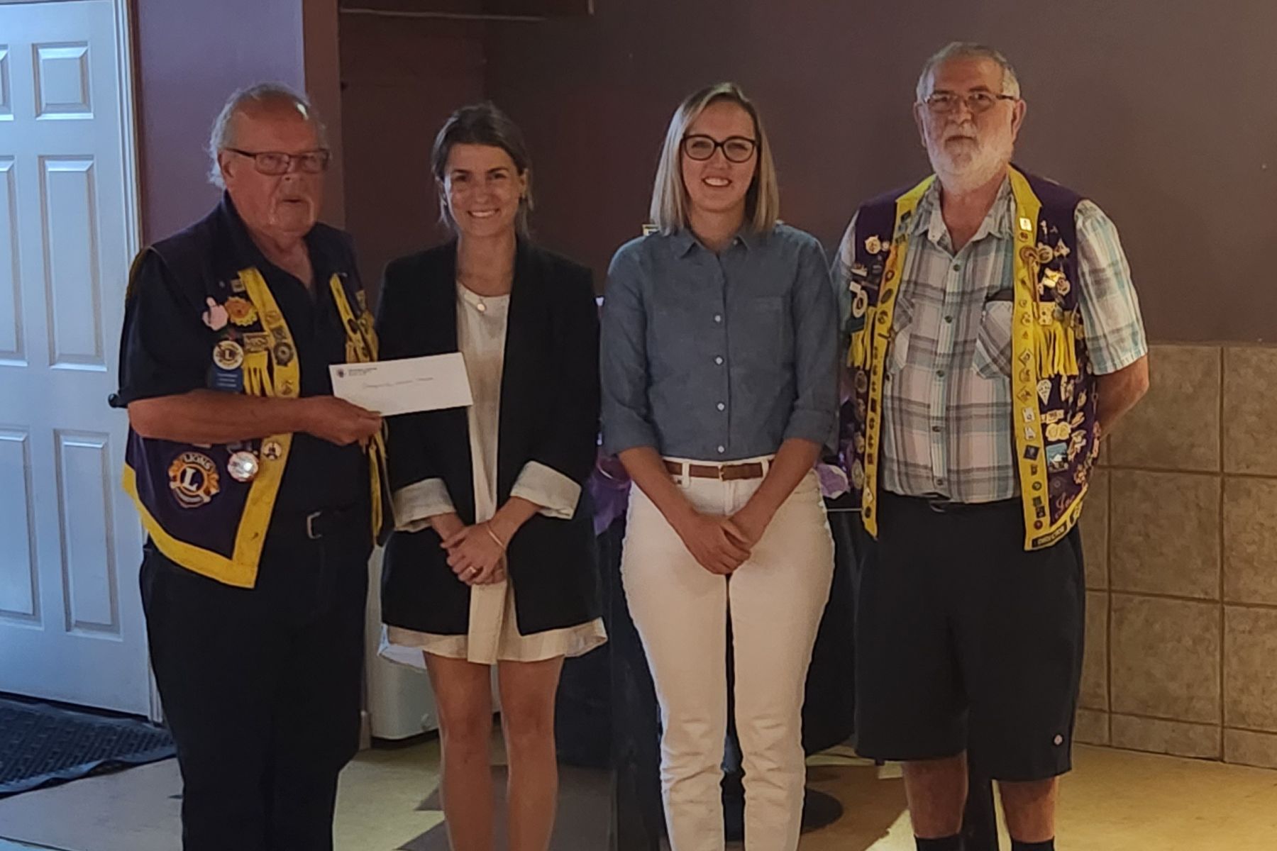 Two male members of the Port McNicoll Lions Club hand a cheque donation to two women representing the GBGH