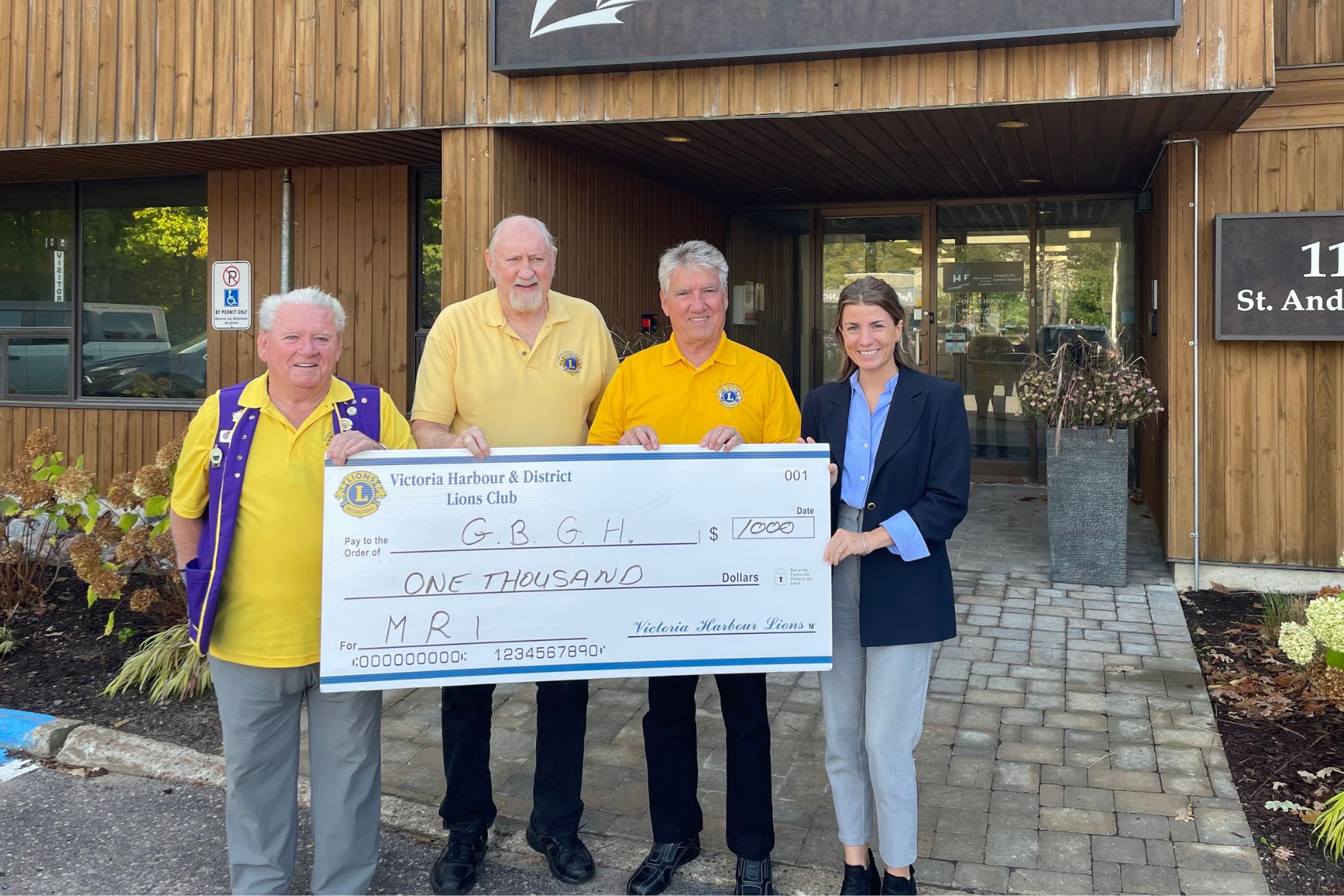 Three men in yellow Lions Club t-shirts and one woman hold a giant cheque made out to GBGH for $1, 000 from the Victoria Harbour Lions Club.