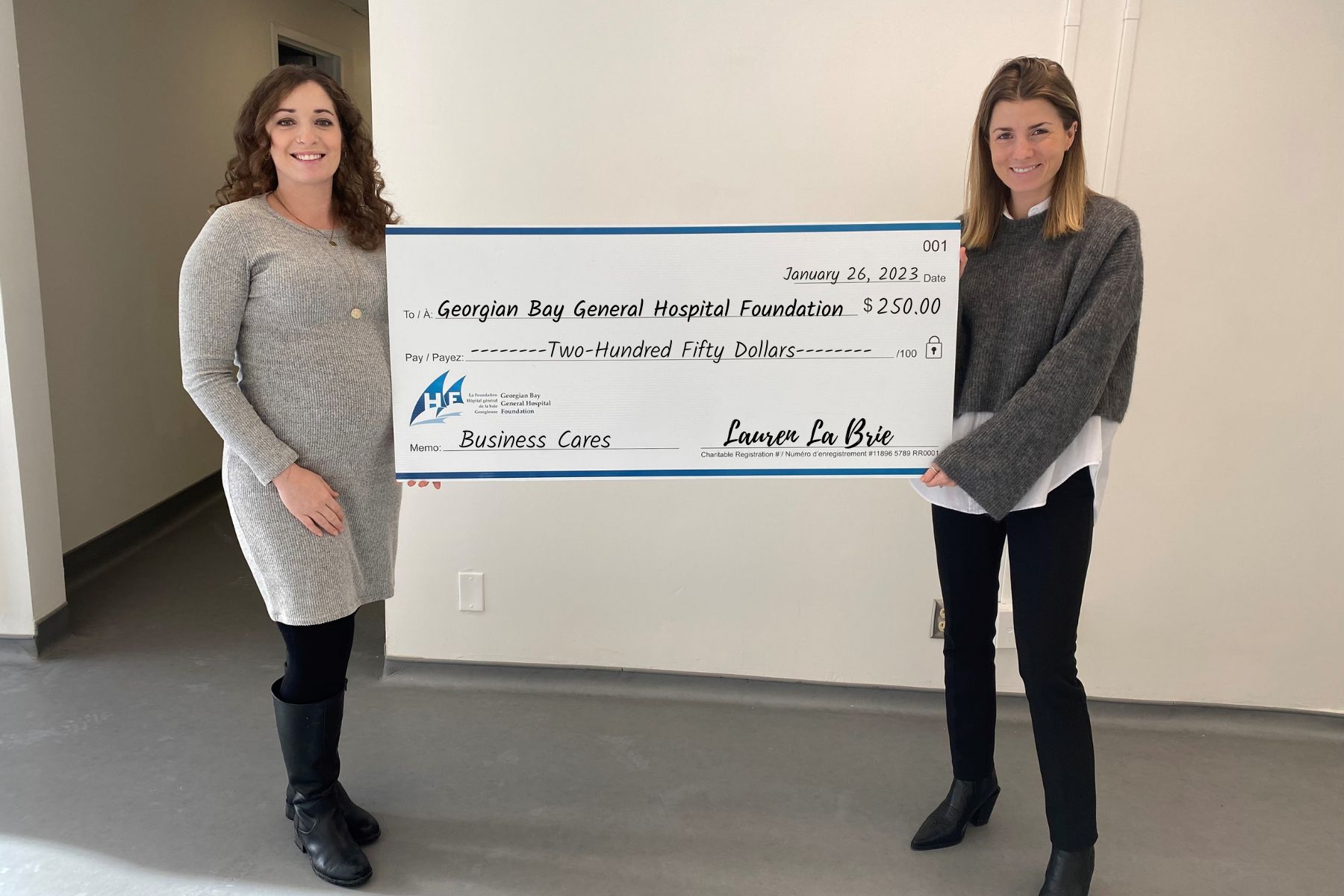 Two women holding a giant cheque for $250 to GBGH Business Cares from Lauren LaBrie