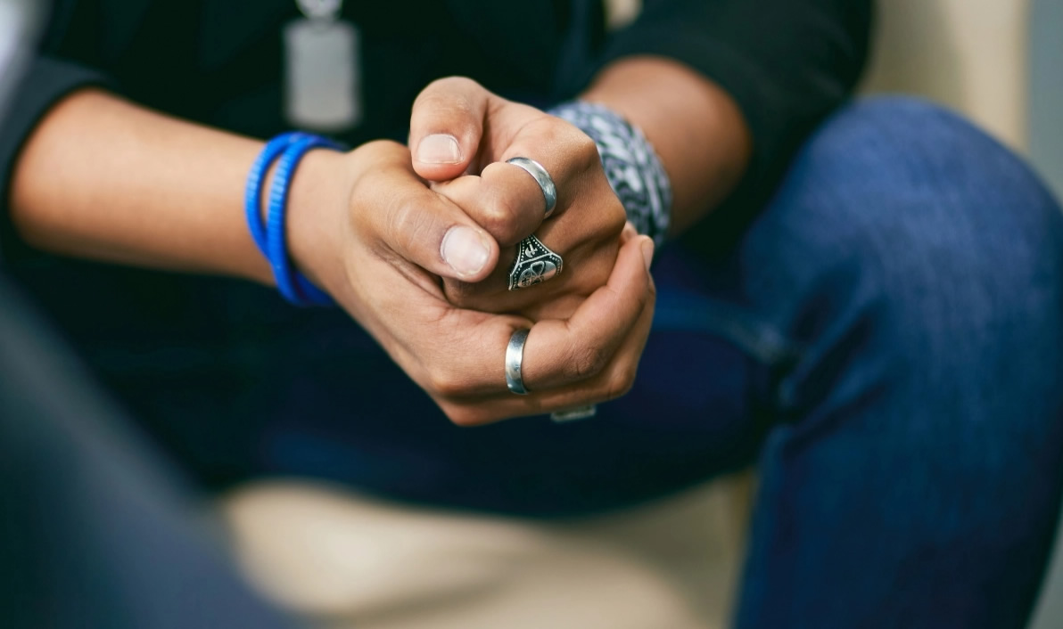 closeup of hands with rings on the fingers including a ring with a skull on it